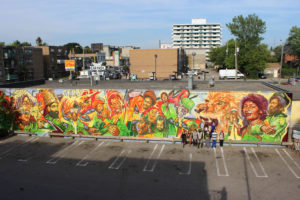 Large-scale mural called Reggae Lane in Toronto's Little Jamaica. It is in orange, red, yellow and green colours of historical figures and musicians