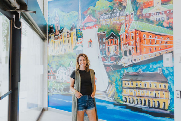Artist Connie Wheaton stands in front of her BMO mural in Fredericton