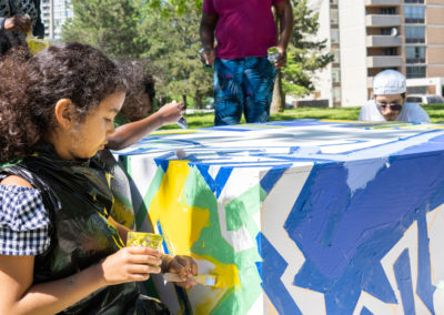 a participant paints at an event in the From Weeds We Grow public art programming