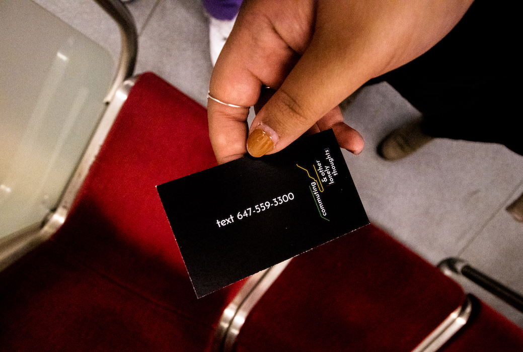 Close-up photo of a small black card with white texts that read "text 647-559-3300, commuting & other lonely thoughts" with green and yellow lines representing the Toronto subway line