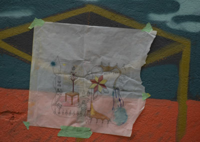 Photo of Shelby Gagnon's mural concept sketch taped onto the site with green painters tape. the wall is painting colours of teal, brown and red.