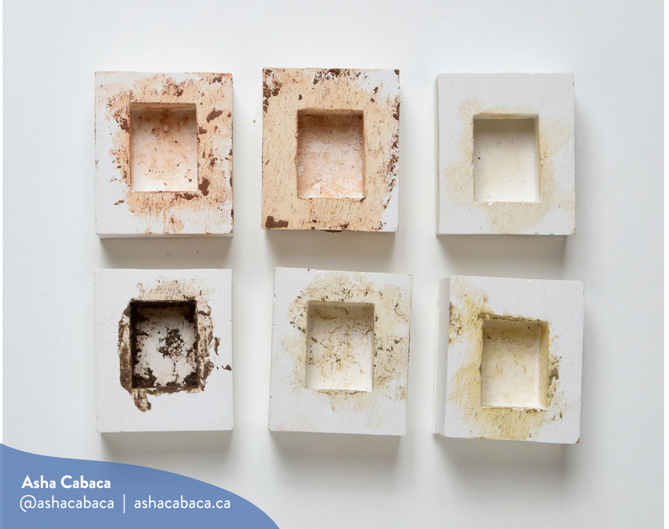 Horizontal photo of artwork by Asha Cabaca, it features six moulds used for shaping six kinds of mud/clay on a white surface. There is a watermark in blue that has Asha’s name, Instagram handle (@ashacabaca) and website (ashacabaca.ca).