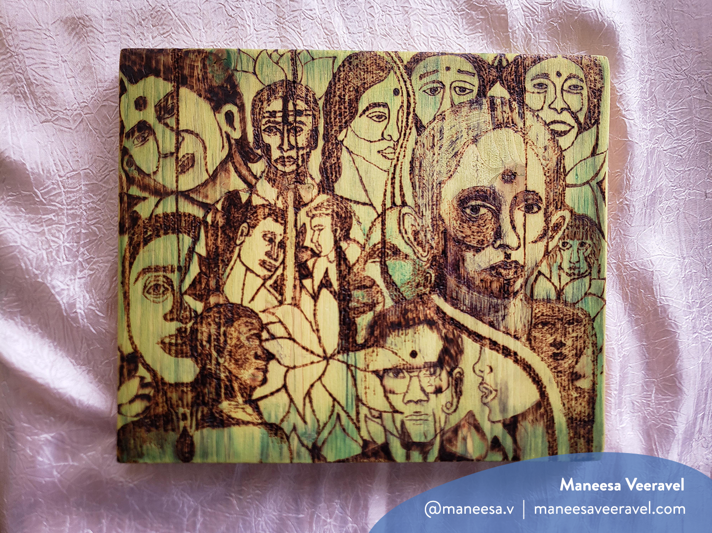 Horizontal photo of wood-burned artwork on a pink fabric background by Maneesa Veeravel. It features drawings of different faces on a yellow and green wood canvas. The image has a watermark with Maneesa’s name, Instagram handle (@maneesa.v) and website (maneesaveeravel.com)