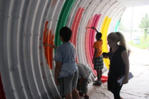 Community members and youth painting the inside of a pedestrian underpass (Dufferin Beltline in Toronto)