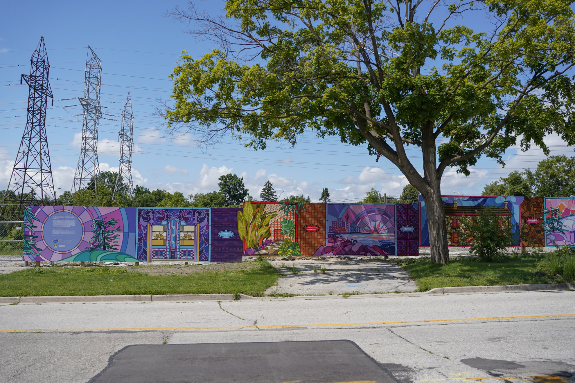 A vibrant outdoor mural on hoarding features various colourful designs and patterns.