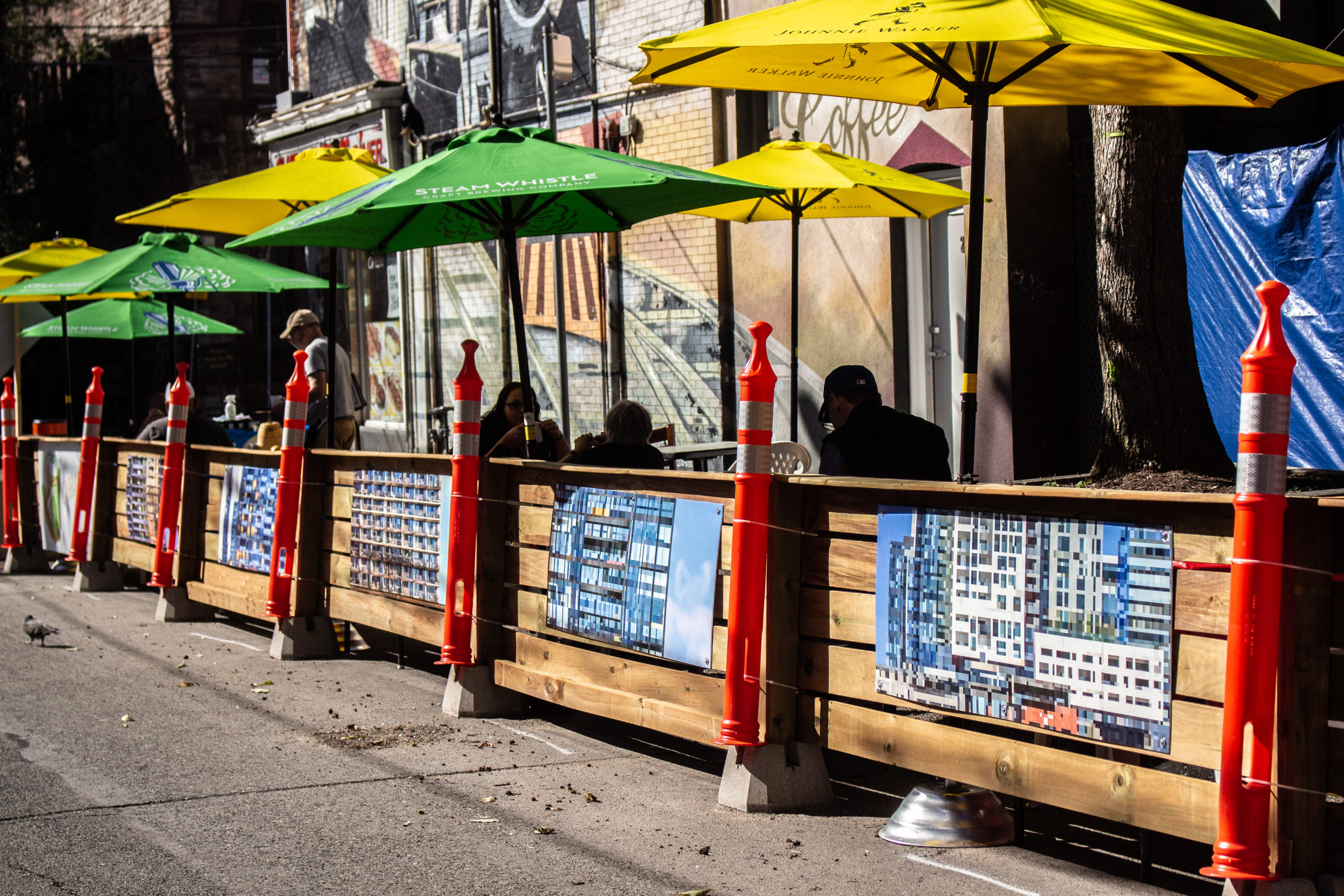 Duncan C. McLean's Main St exhibit that has high-rise condos in Toronto, there are patio umbrellas and street visible