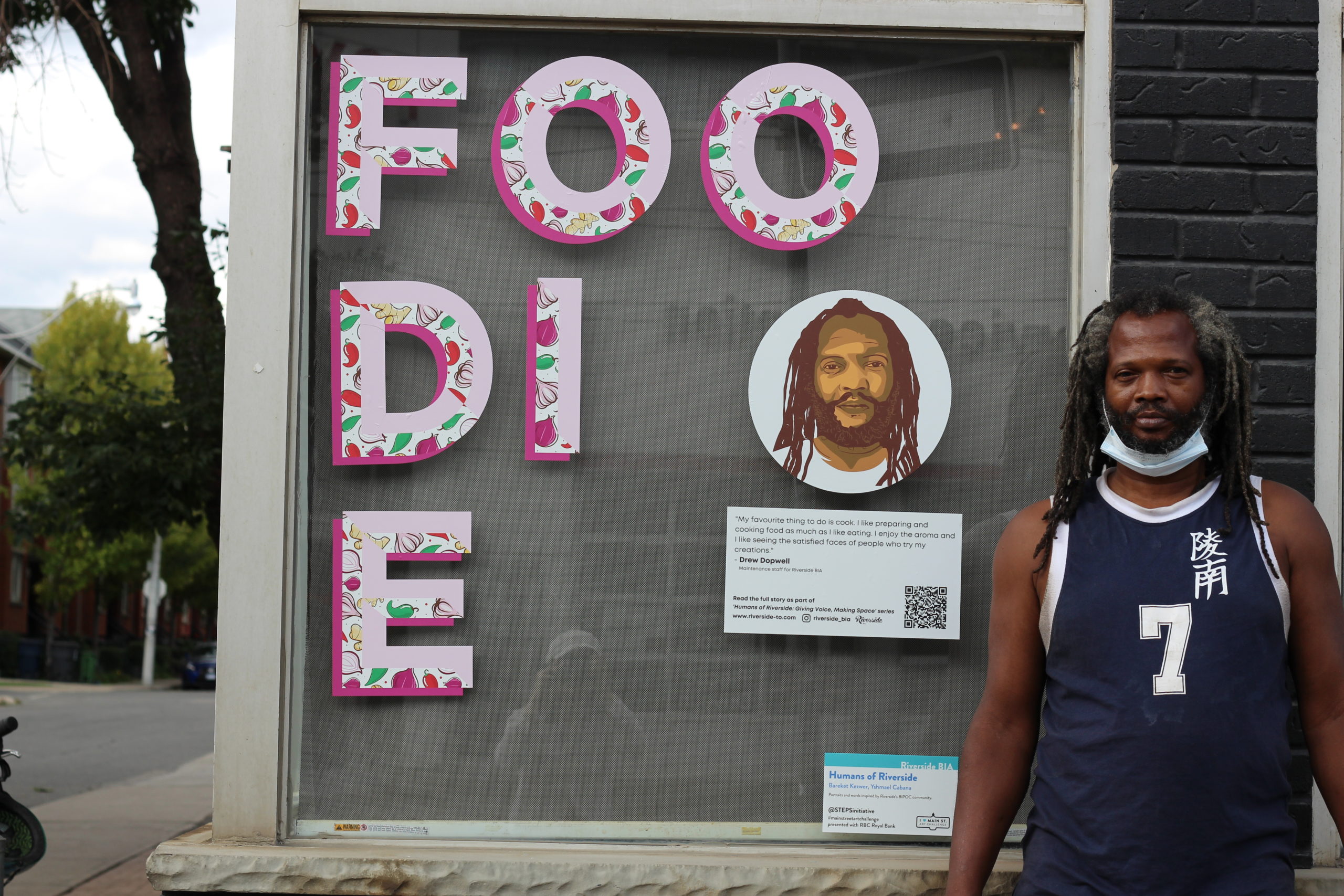 A person standing next to a window decal with an illustrated type and portrait that says Foodie.