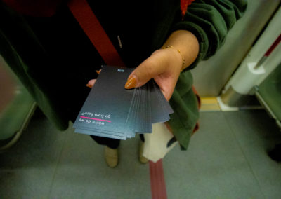 A hand holding a stack of black cards with white text that reads "where do we go from here?" on a TTC subway