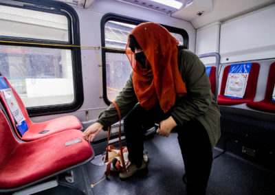 Photo of Yasmeen Nematt Alla putting business card on the red seat of a TTC bus