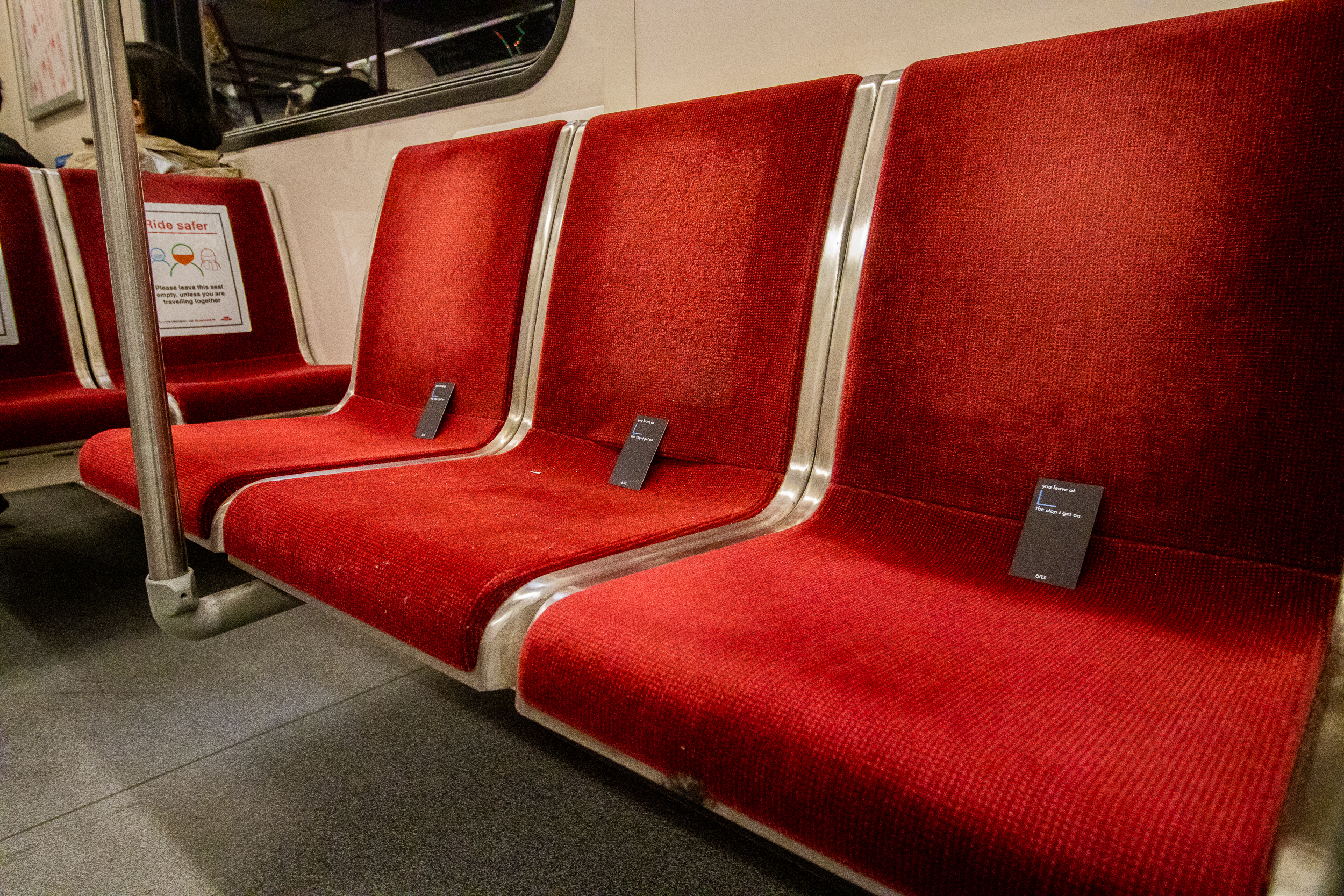 Photo of black business cards with white text place on three TTC subway seats.