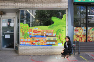 Person crouching next to a window mural installation