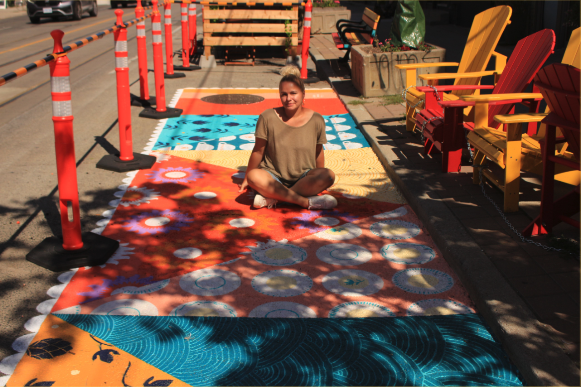 An aerial shot of Bareket Kezwer and another artist painting a ground mural on sidewalk.