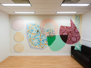 Photo of colourful indoor mural featuring overlapping shapes and patterns