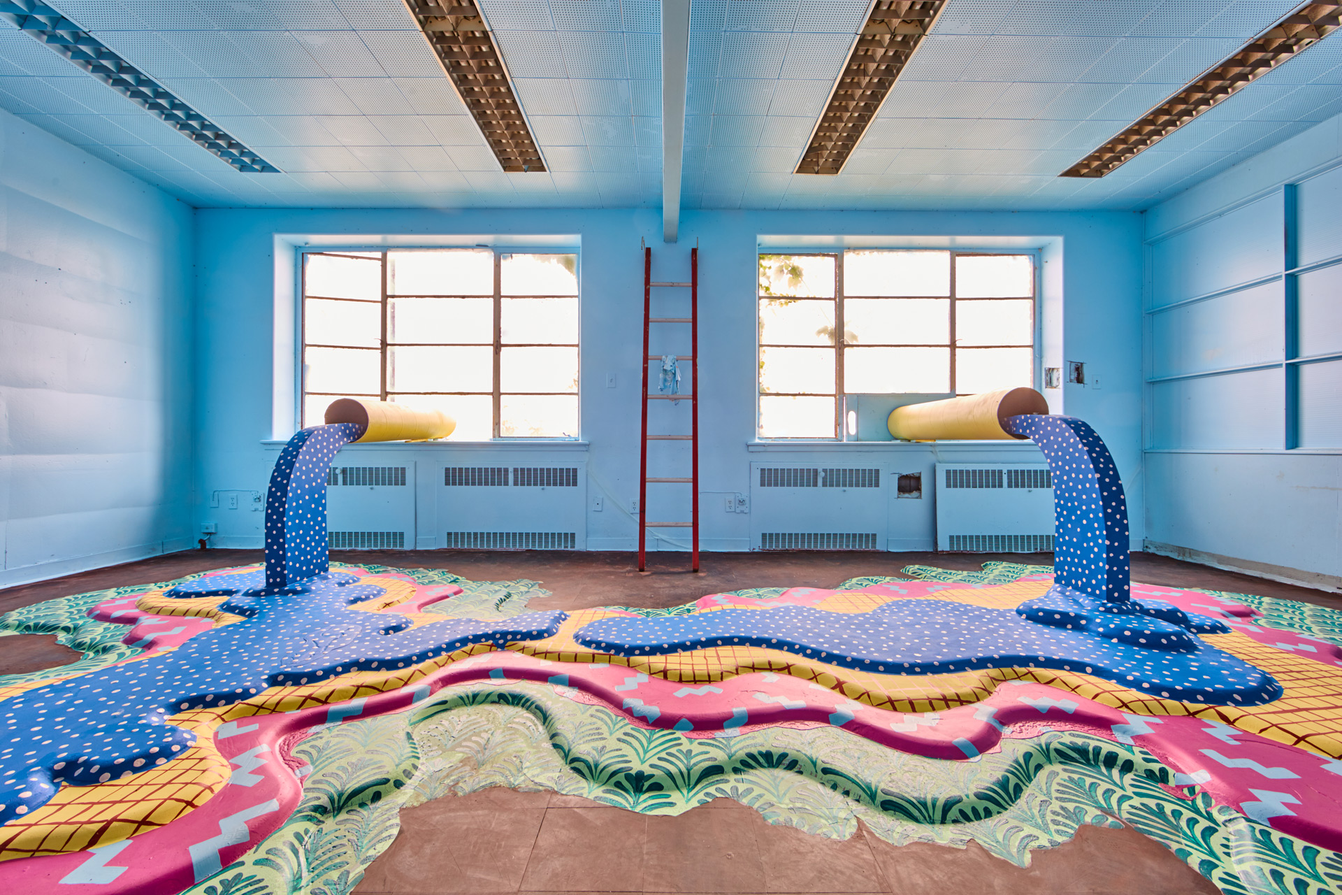 Photo of abstract are pieces featuring two pipes with colourful liquid pouring onto the floor