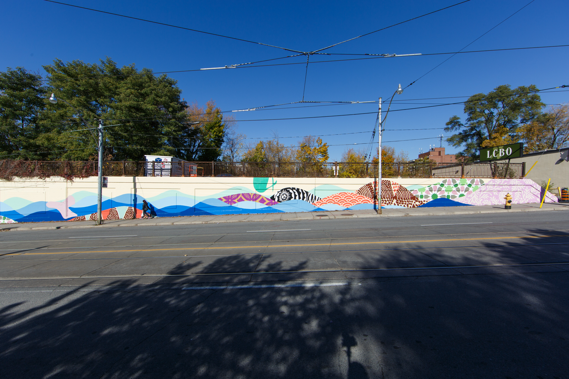 Photo of outdoor mural on a long wall showing abstract scenery