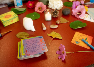 Photo of postcards with writing and art on them along with leaves and flowers on a table.