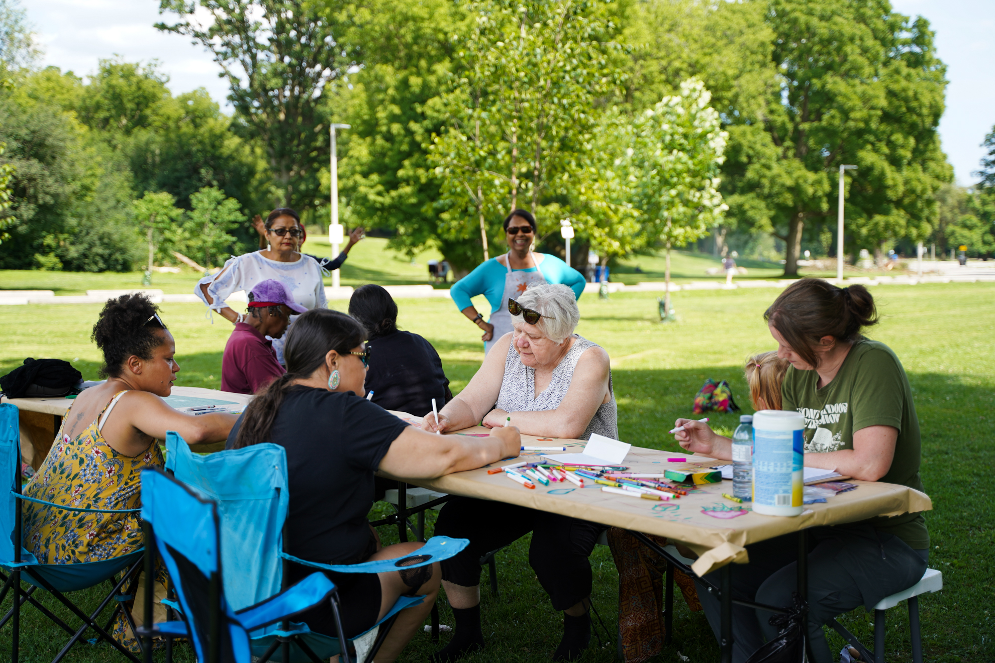 Art workshop participants in a park and drawing on a tabletop together as part of STEPS Public Art's From Weeds We Grow program