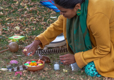 Artist Richa Baghel lighting candles in a clay bowl on the grass