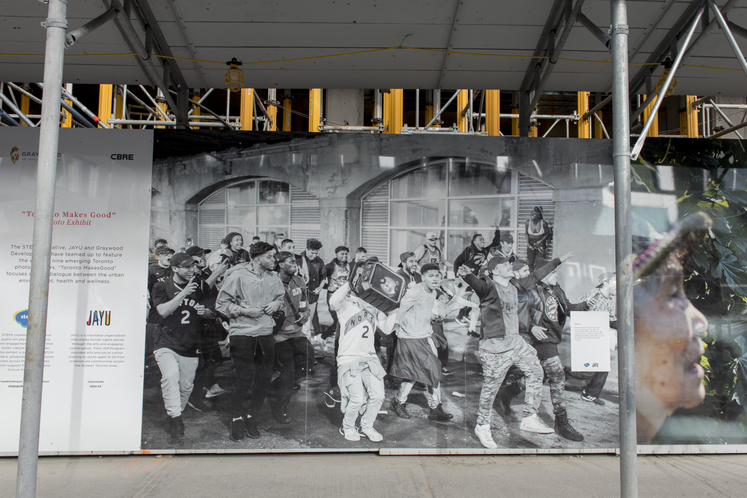 Toronto Makes Good Hoarding Exhibit featuring black and white photograph by Stephen Attong of a crowd celebrating the Toronto Raptor's Game Six win in 2019