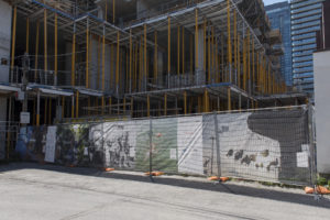 Toronto Makes Good hoarding exhibit with large photography on mesh that is hanging on fencing that surrounds a construction site.