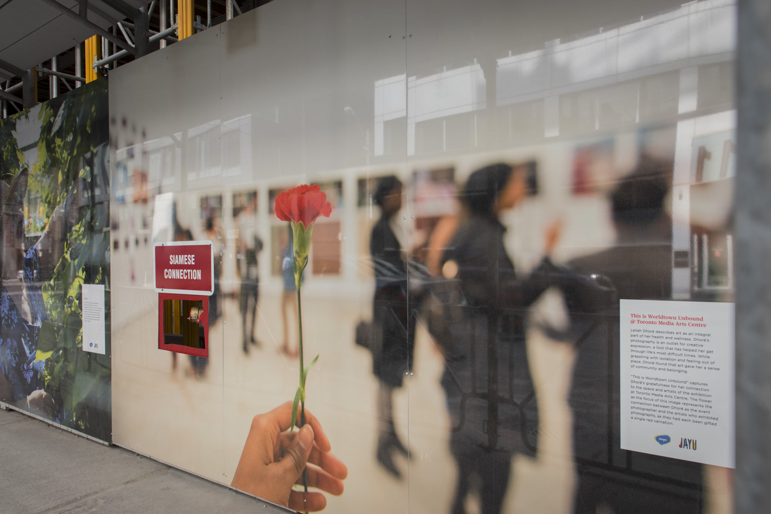 Toronto Makes Good Hoarding Exhibit featuring artwork by Leilah Dhore of a person holding a rose in an art gallery with people in the background.