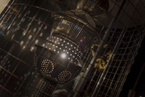 Close up of Light Strainers, a stainless steel kinetic light sculpture made of kitchen colanders with light projecting through the colanders