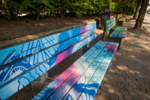 Close-up photograph of brightly painted benches with cartoons and fun designs by Mahmood Hosseini