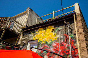 A low angle image of Chris Perez's mural of red and yellow flowers on the back of a building