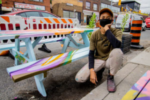 Leone McComas crouching and posing beside her painted picnic table
