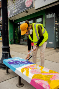 Leone McComas painting a bench with vibrant colours