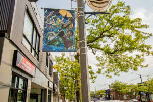 Danielle Hyde's street light banner hanging with an intricate and detailed design featuring people and the city