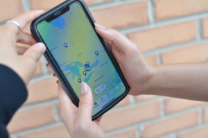 A close-up photograph of a people holding an iPhone with the STEPS Public App opened to a map of Ontario with locations of public art projects pinned.