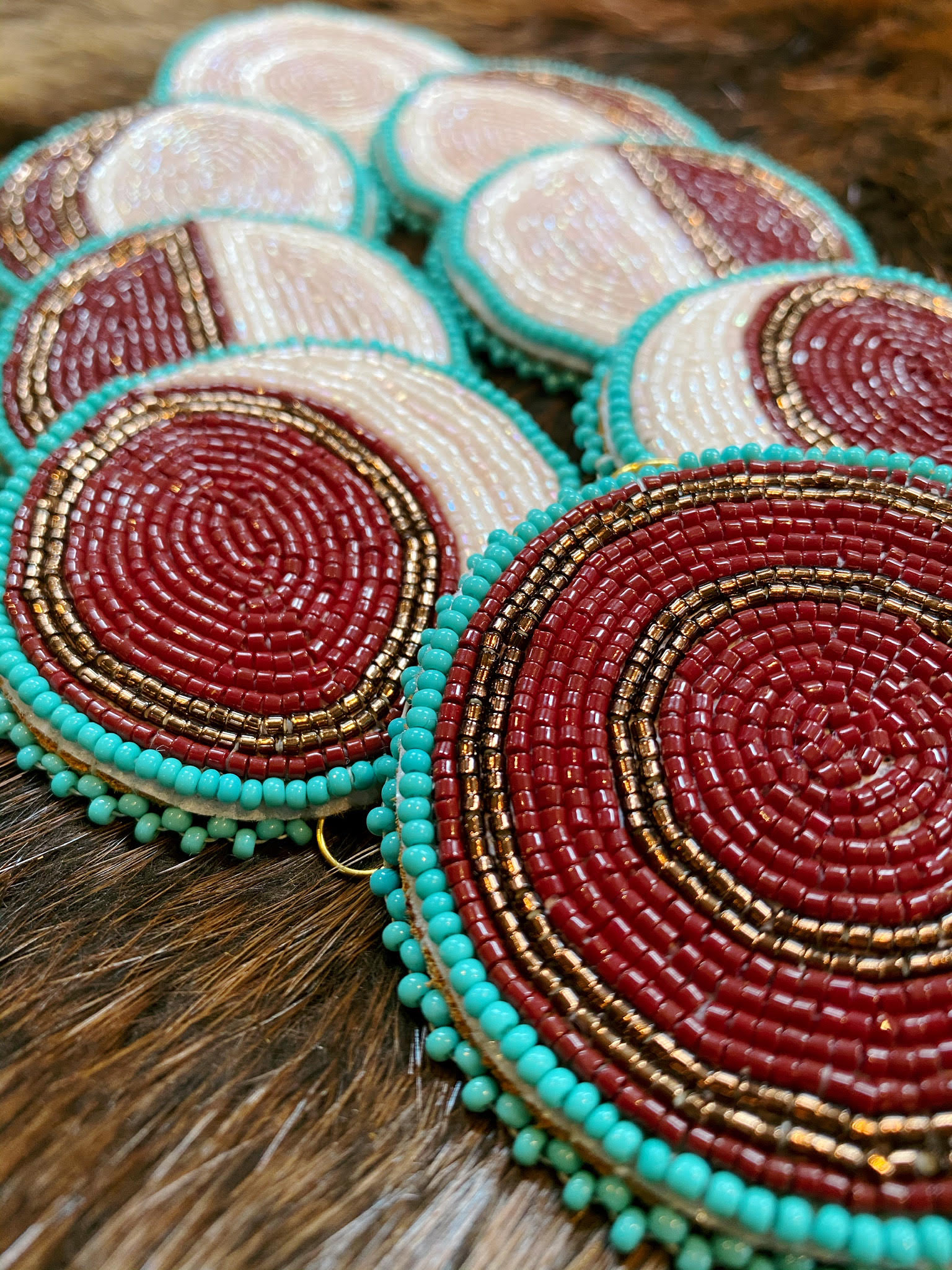 photo of beading work by artist lindsey lickers, red, teal and white beads in a circular design showing the moon phases