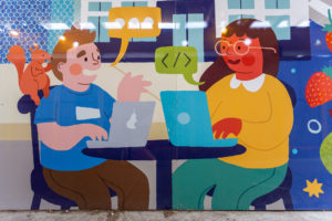 ilustrated image of two people seated at a table with their laptops in conversation