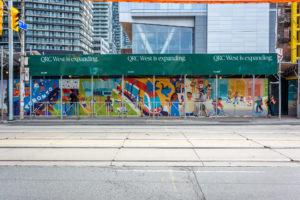 Photograph if an illustrated mural on a piece of construction hoarding