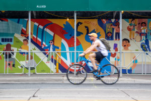 A cyclist rides past a mural depicting a subway car