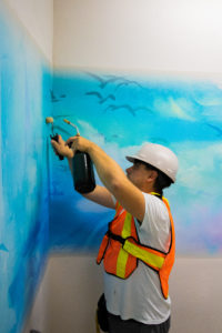 Person applying mural to wall