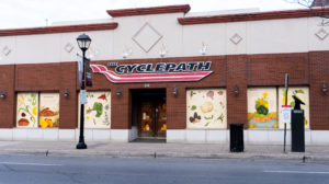 Photo of a CyclePath storefront that features vinyl mural on the window showcasing Indigenous foodways and foraging foods