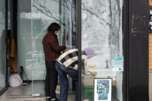 Two artists installing their artwork in a window display