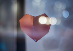 Close up photo of a red paper heart hanging in the air