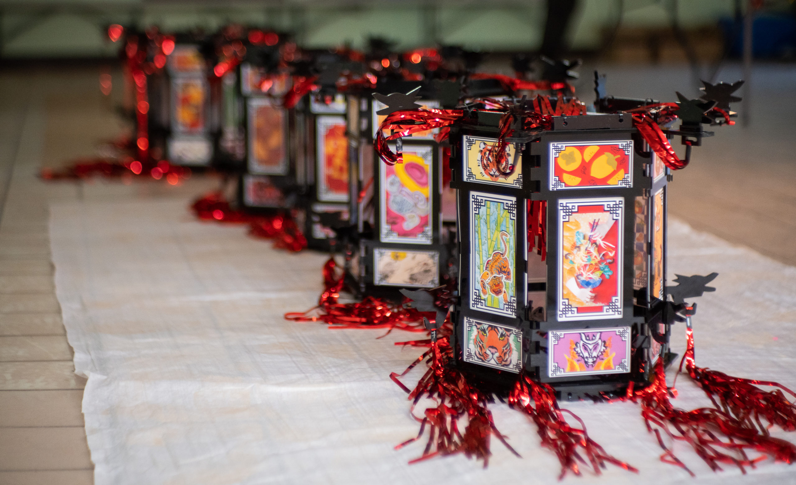 Landscape photo of black acrylic lanterns for Yue Moon with community artwork framed with tinsel