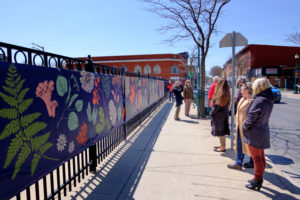 Pedestrains gather around the new fence banner depicting flora and fauna