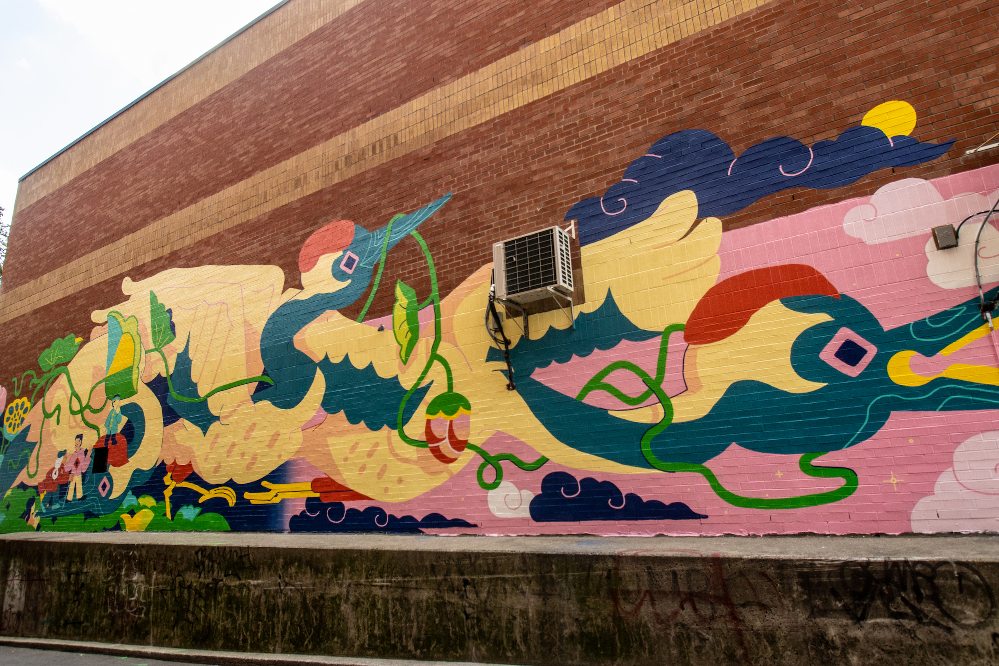 A large-scale mural on a brick wall in Toronto's Chinatown by Wenting Li. There is imagery of cranes flying and people interacting with each other.