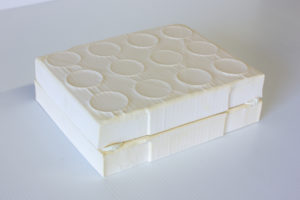 An art piece made from plaster and chewing gum by Taylor Buss. It is two rectangular plaster casts of a shallow cardboard box resting on top of each other.