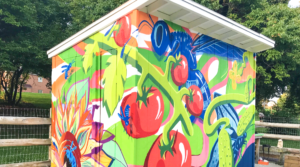 landscape photo of a garden shed with a colourful mural with abstract shapes and a tomato plant