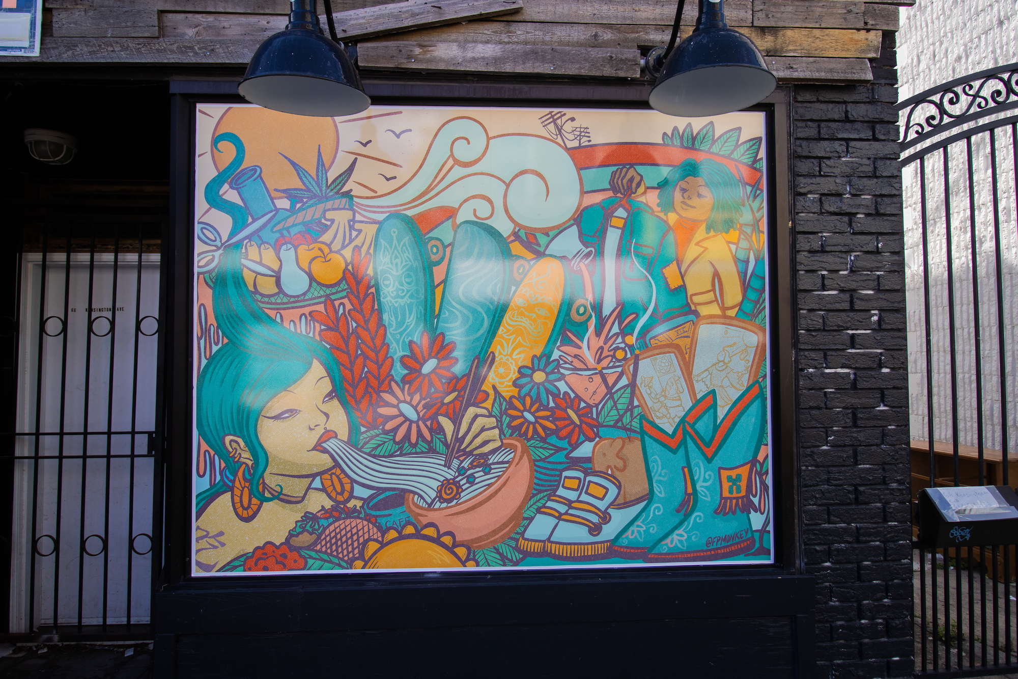 A large window installation with a colourful digital mural by artist FP Monkey. The artwork is in warm golden colours with fun characters, foods, clothing, and other symbols of Toronto's Kensington Market neighbourhood