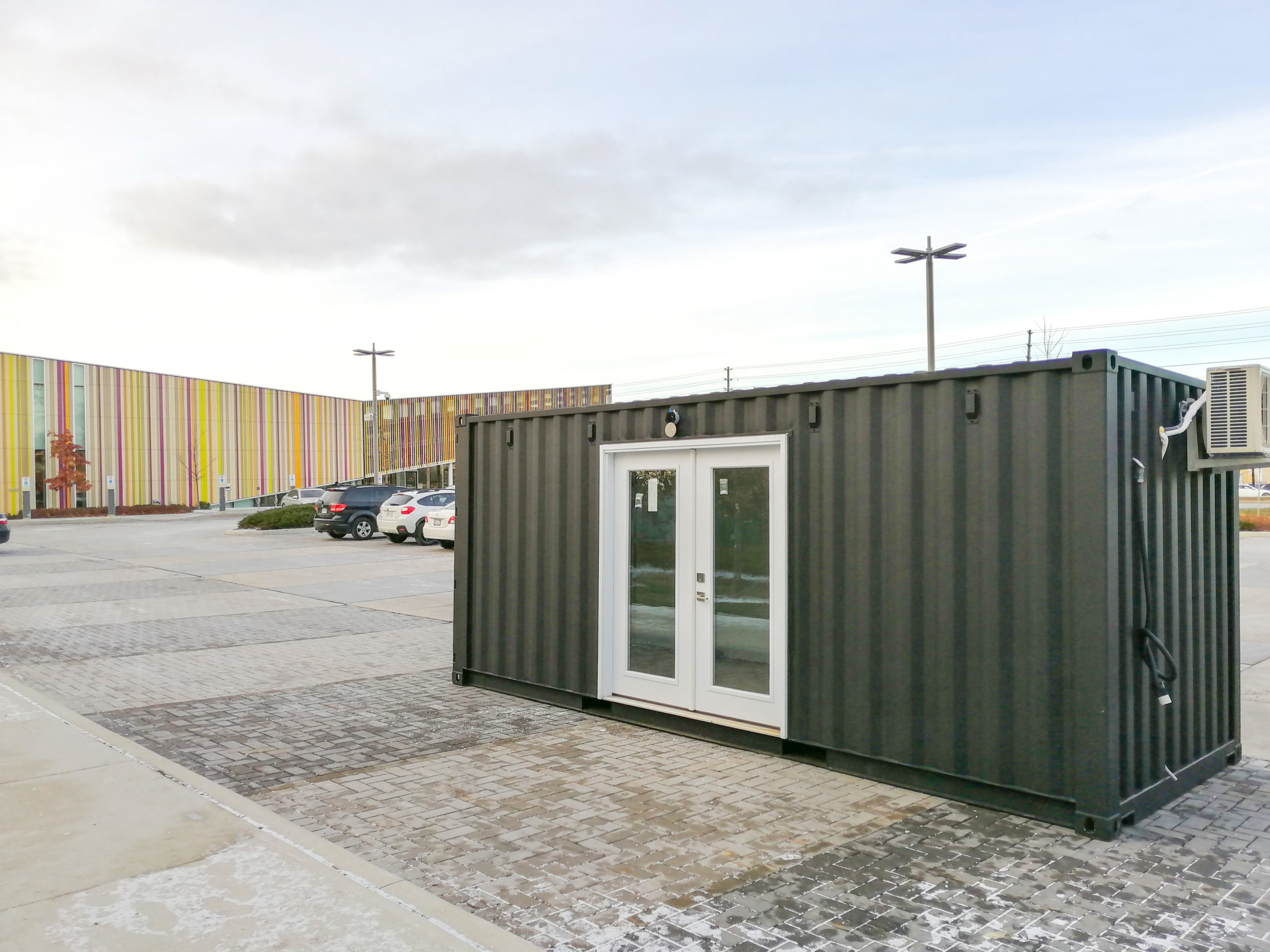 Landscape photo of a black shipping container with white doors, sitting in a parking lot.