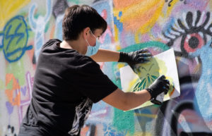 participant uses a stencil to contribute to a mural painting