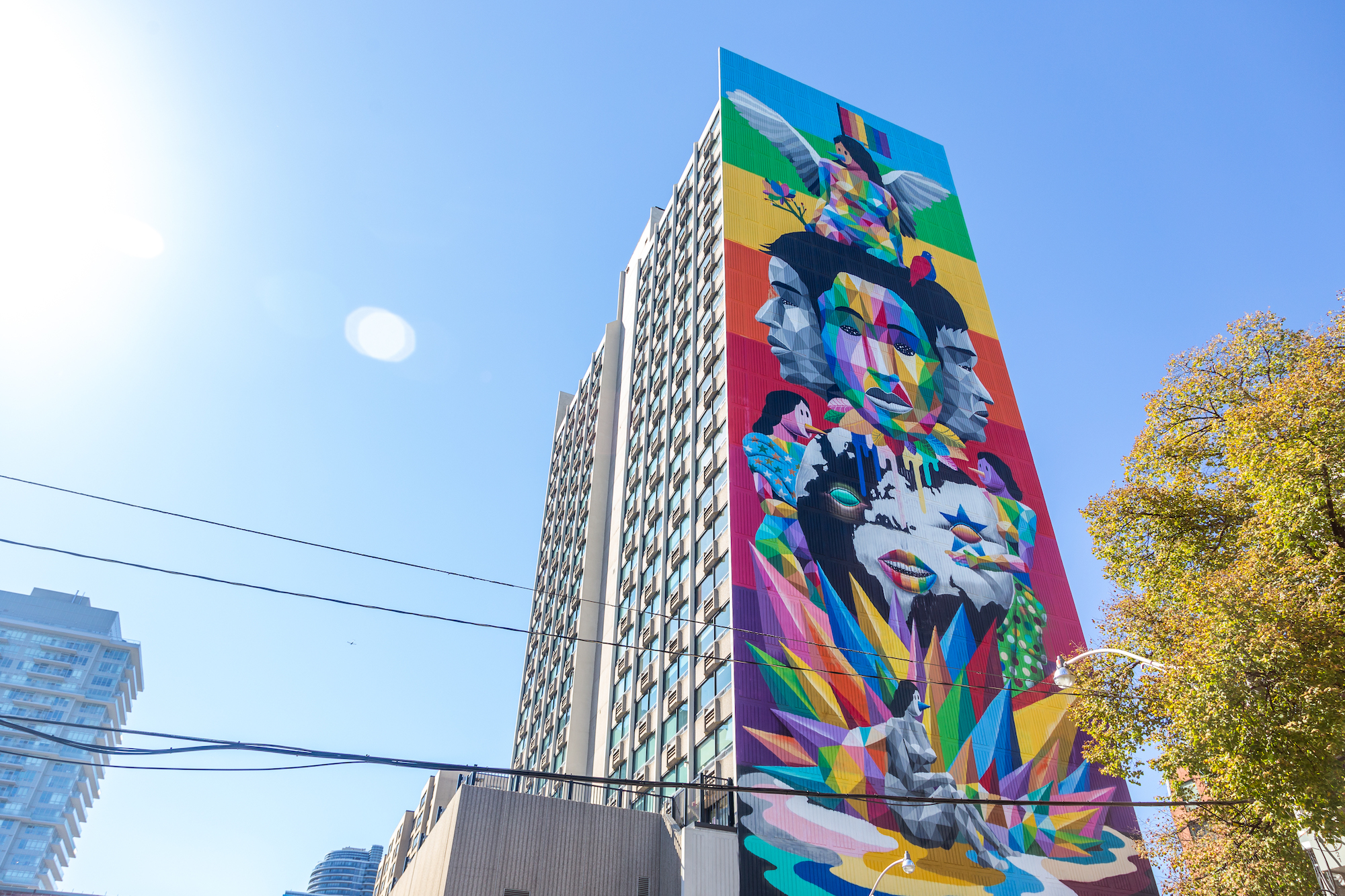 A large 23-storey mural by Okuda San Miguel called Equilibrium Mural in Toronto. Each section is a different colour of the rainbow with geometric imagery of the pride flag, diverse faces,