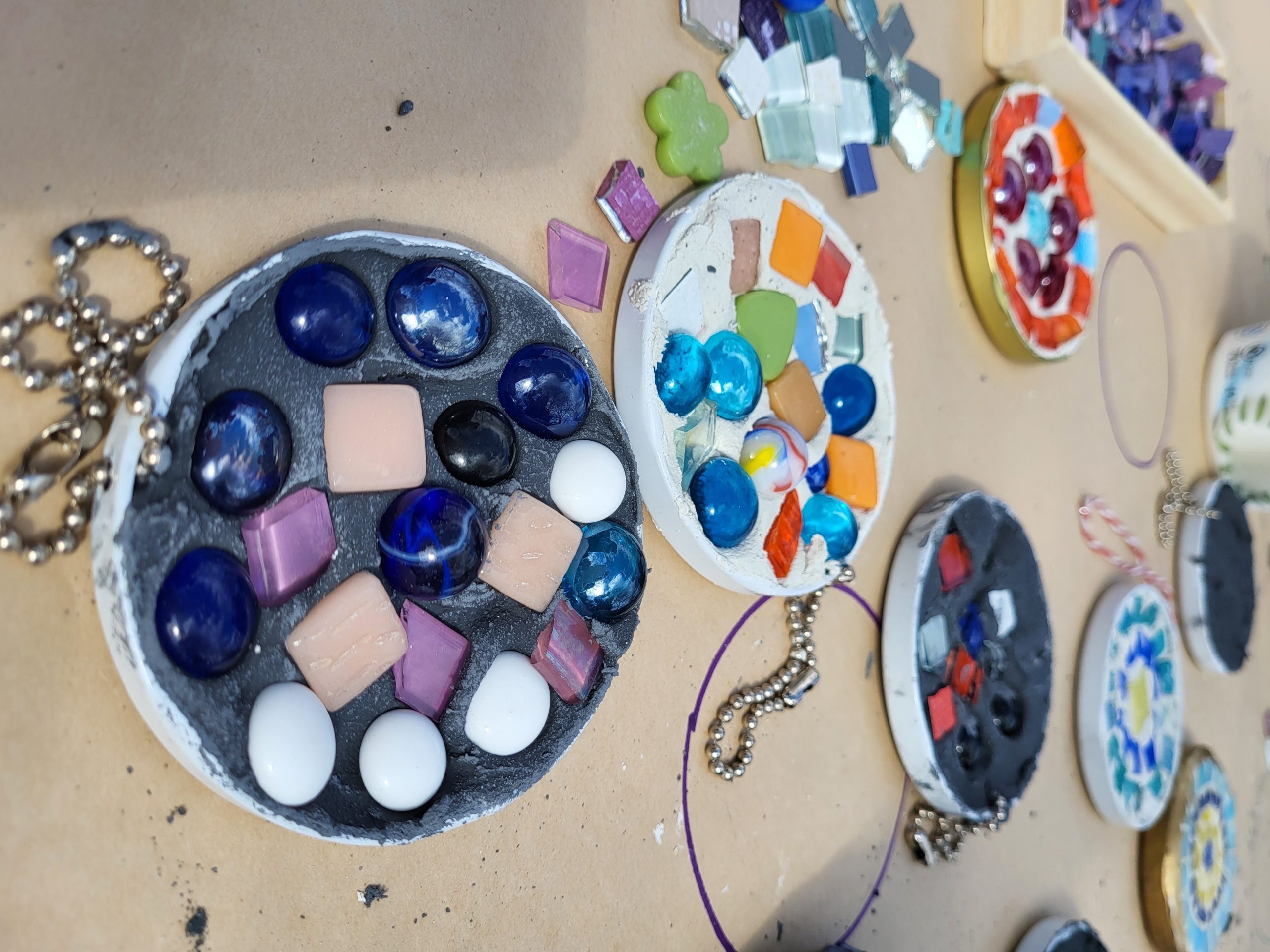 Workshop materials for a mosaic workshop with colourful beads and tiles on kraft paper